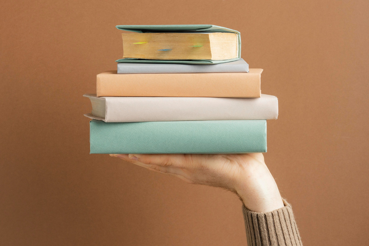 Imagem com uma mão segurando cinco livros simbolizando editoras independentes