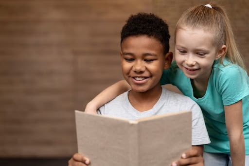 um menino e uma menina lendo um livro para simbolizar o Dia Nacional do Livro Infantil