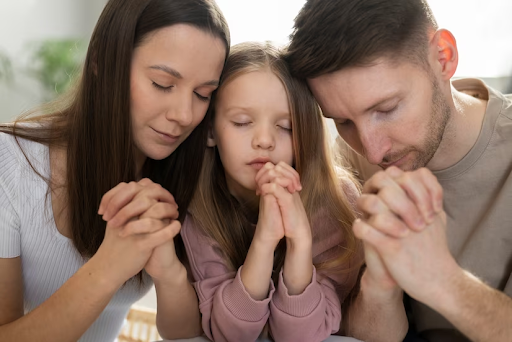 casal rezando com a filha para simbolizar texto sobre livros religiosos