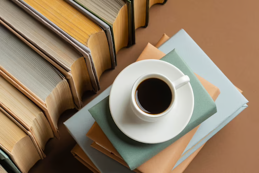 um café e vários livros ao redor para simbolizar o Dia Nacional do Café